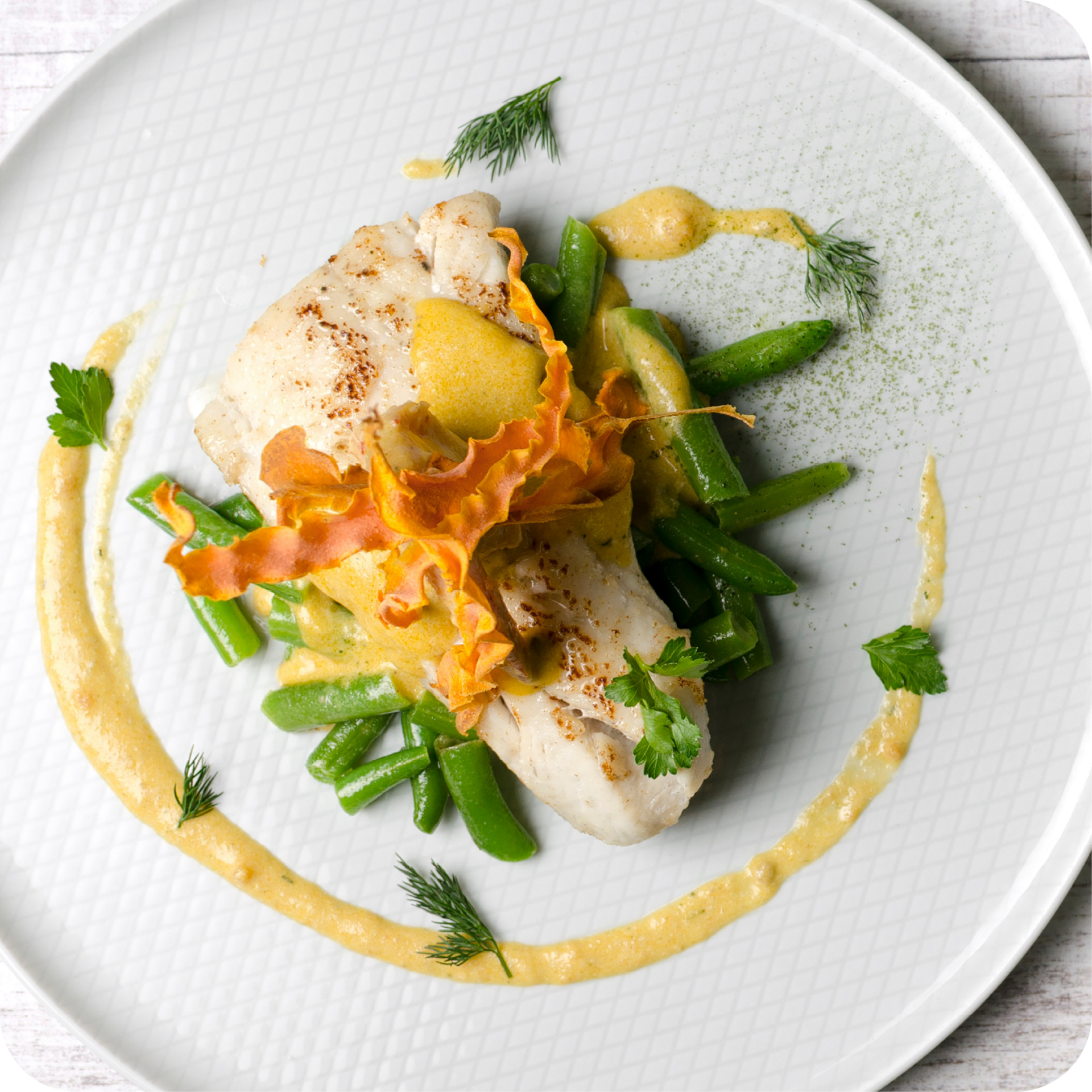 Blauer Teller mit gebratenem Fischfilet, Tomaten, grünem Gemüse und brauner Sauce angerichtet.